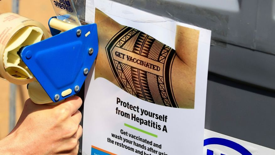 Sign telling people to get vaccinated to protect against Hepatitis A at the Neil Good Day Center on 17th Street downtown in San Diego, California. Image Credit: Eduardo Contreras/The San Diego Union-Tribune via AP