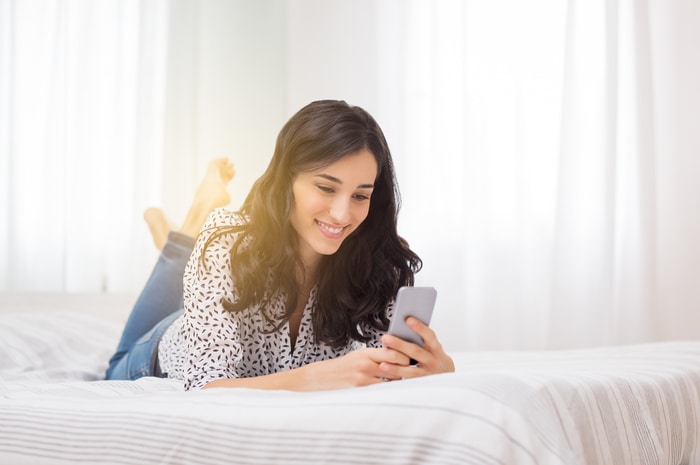 Woman Smiling in Bed with Phone