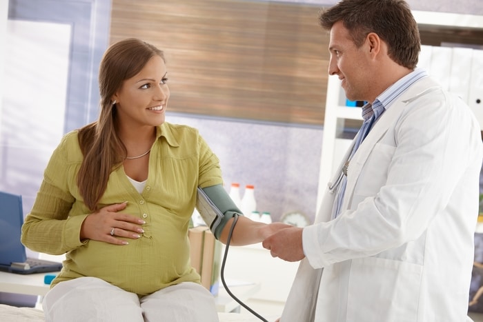 Smiling Pregnant Woman Consulting Doctor